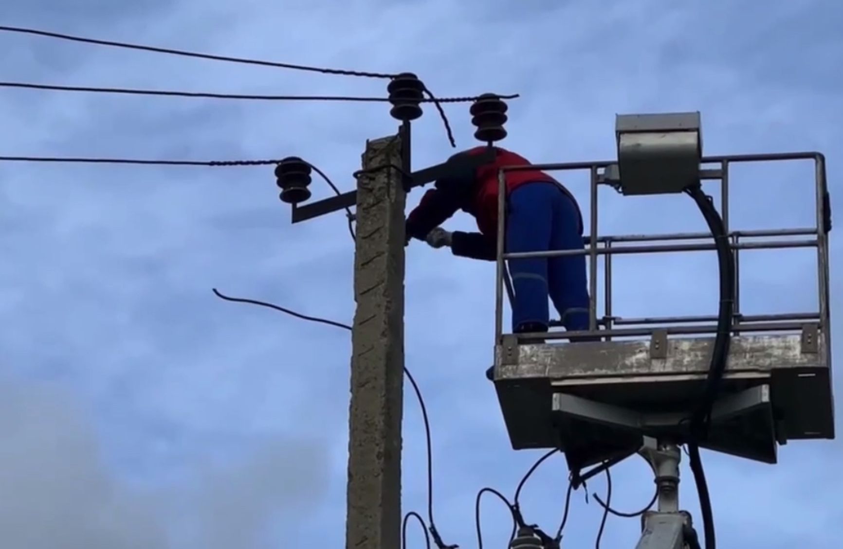 Рабочие снимают со столба незаконно протянутые провода, питающие ферму в Новом Хушете.