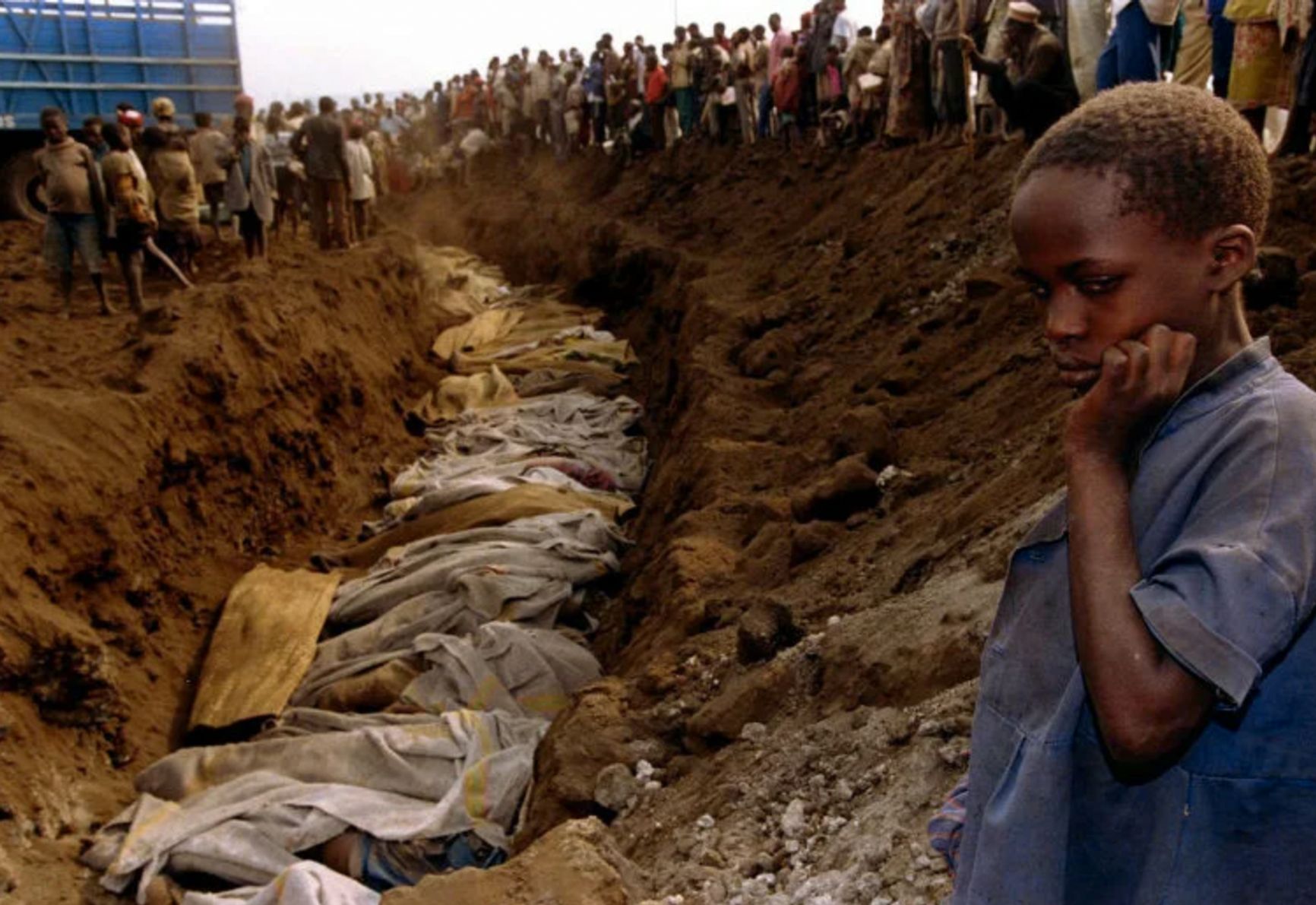 Мальчик тутси на фоне братской могилы, в которой похоронены все его родные